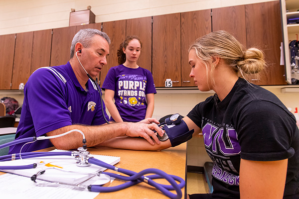 instructor demonstrating how to test blood pressure with students