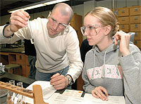 Two students looking at test tube, recording results