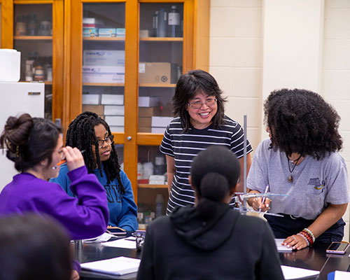 group of students and professor having a discussion in a lab