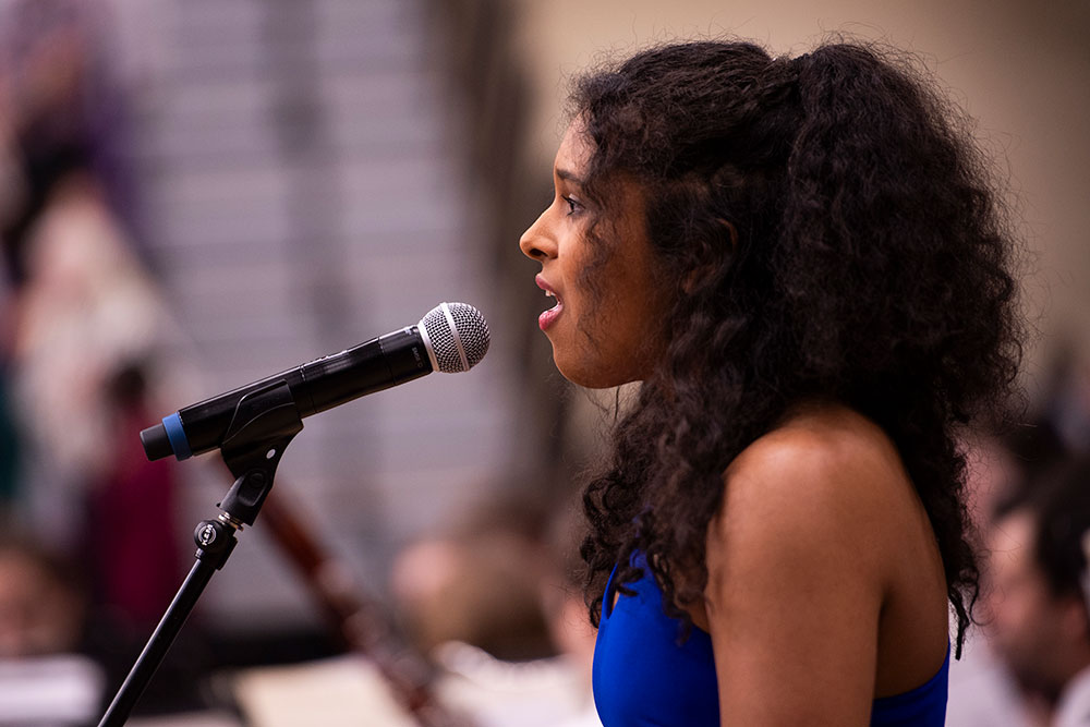 a student singing at a microphone in a performance setting