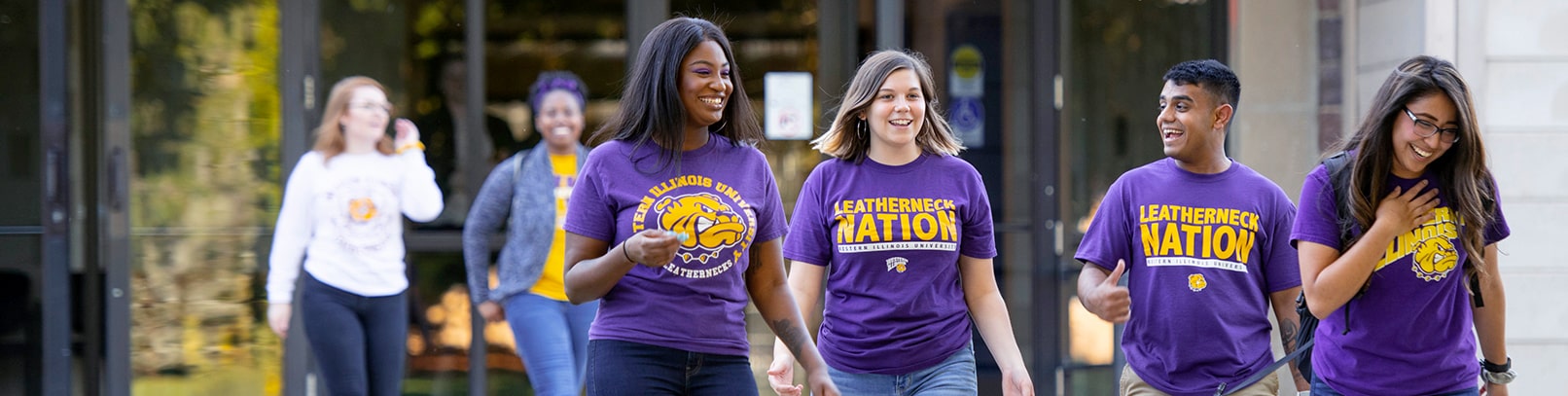Students with purple and gold WIU t-shirts walking and laughing. 