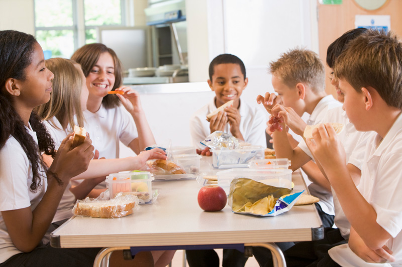 kids sitting around a lunchroom table eating