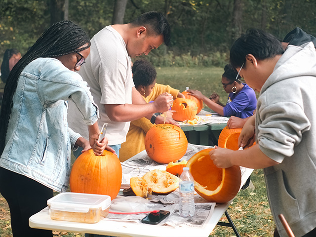 students carving pumpkins outdoors