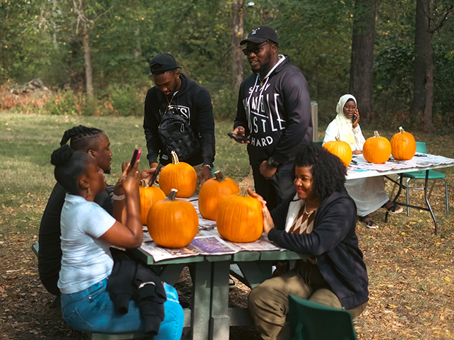 students carving pumpkins outdoors